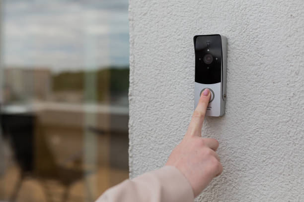 la mano della donna usa un campanello sul muro della casa con una telecamera di sorveglianza - pushing women people wall foto e immagini stock