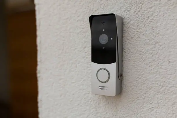 Photo of doorbell on the wall of the house with a surveillance camera