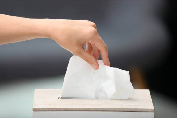 istock Woman taking paper tissue from holder on blurred background, closeup 1352624737