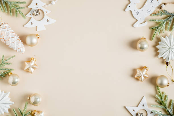 istock Christmas frame. Elegant Christmas card with fir branches, boho style white stars, baubles, pine cone decoration on beige background. Flat lay, top view, copy space 1352642974