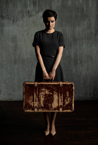 jolie femme dans une robe à pois classique tient une valise en cuir à l’ancienne dans un style rétro. - polka dot suitcase retro revival women photos et images de collection