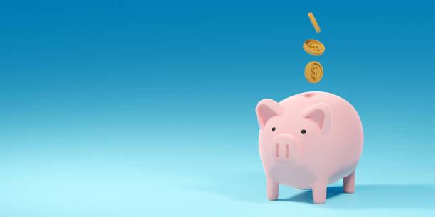 istock Coins falling into a pink piggy bank on blue background with copy space 1352644301