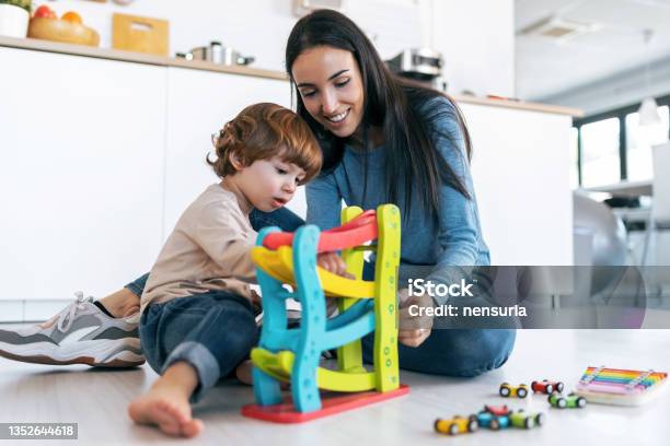 Young Beautiful Mother Playing On The Floor With Her Son In Living Room At Home Stock Photo - Download Image Now
