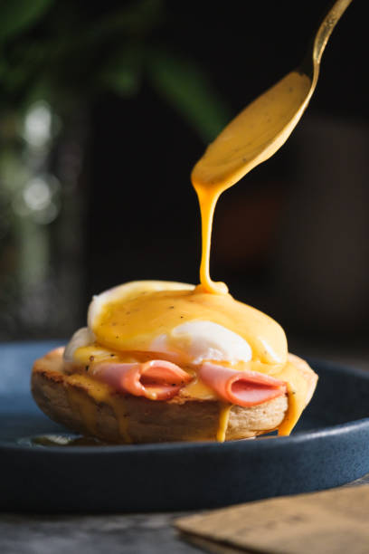 ovo benedict com molho hollandaise em prato azul escuro na mesa na cozinha - hollandaise sauce fotos - fotografias e filmes do acervo