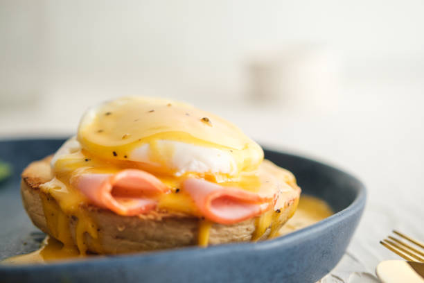 istock egg Benedict with hollandaise sauce on dark blue plate on table in kitchen 1352645957