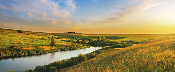 красивый летний пейзаж с красочным закатным небом над спокойной рекой и холмами - prairie стоковые фото и изображения