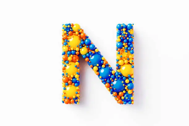 Colorful capital letter N made of many spheres sitting on white background. Horizontal composition with clipping path and copy space. Directly above.