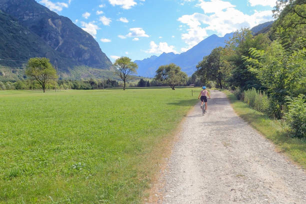 istock Female mountain biker rides  road through lush valley 1352653420