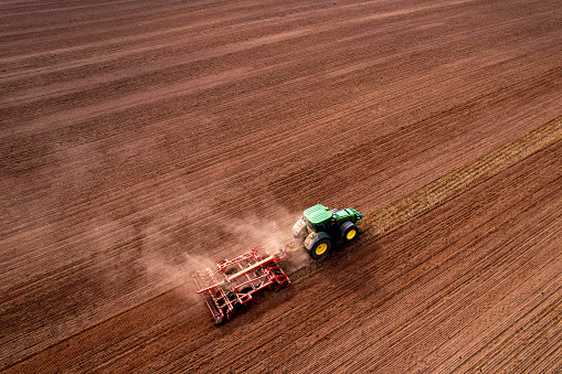 John Deere Tractor with disc cultivator Vaderstad on cultivating field. Agricultural tractor with Plough on Plowed and cultivation field. Soil Tillage and sowing seeds. Russia, Moscow, Sept 30, 2021.