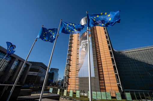 Berlaymont building of the European Commission Brussels in with EU flags flying in autumn 2021. Wide angle shot.