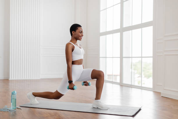 istock Black woman doing forward lunges holding dumbbells 1352656252