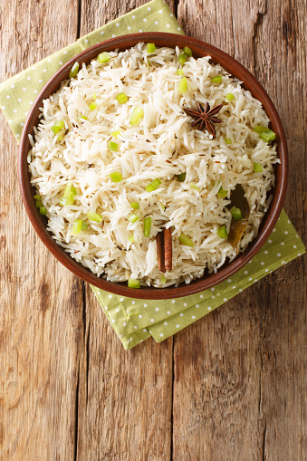 Jeera rice or Zeera rice is an Indian dish consisting of rice and cumin seeds close up in the bowl on the table. Vertical top view from above