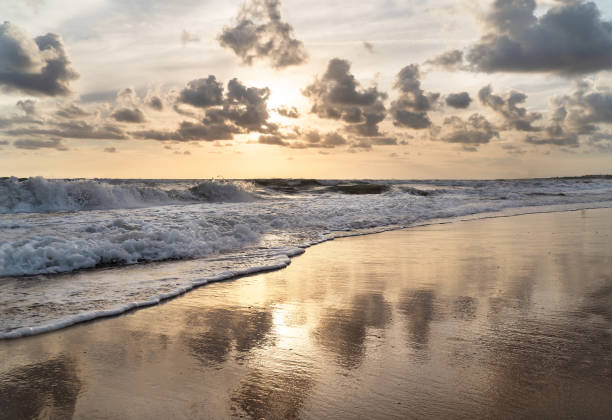istock Sea splashing waves in the setting sun background with beautiful cloudy sky reflection in the water. Travel and tourism concept. Nature background. 1352657872