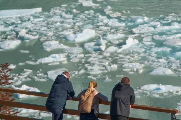 deriva di ghiaccio sul ghiacciaio perito moreno. gruppo di turisti (vista posteriore con messa a fuoco selettiva) che osservano lo spostamento di banchi di ghiaccio bluastro alla deriva su sfondo turchese sfocato dell'acqua del lago argentino, argentina - floe lake foto e immagini stock