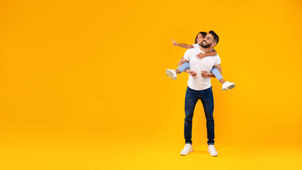 istock Middle-Eastern Father Carrying Daughter Having Fun Over Yellow Background, Panorama 1352658094