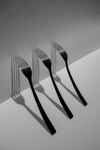 Three forks isolated with long shadows. Black and white. Creative still life art composition.