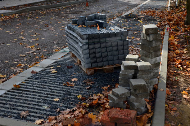 construction of new residential area roadway. parking spaces are made of concrete perforated fittings. the surroundings are fenced with portable fences. pallets of interlocking paving ready for laying construcción de nueva calzada de zona residencial. los espacios de estacionamiento están hechos de accesorios perforados de concreto. los alrededores están vallados con vallas portátiles. palets de pavimento entrelazado listos para la colocación