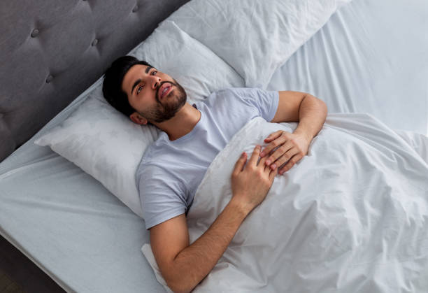 istock Thoughts in head not let fall asleep. Young arab man lying in bed and looking at ceiling, thinking of something 1352662139
