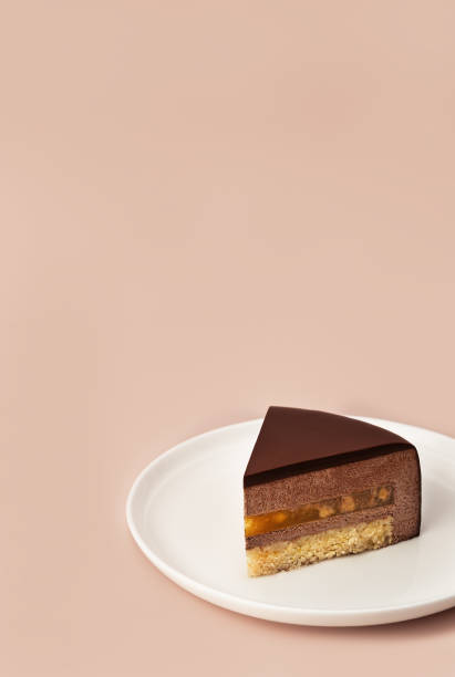 istock Delicious chocolate mousse cake slice with the layers and texture displayed on pastel coffee colored background. Close-up. Copy space. 1352662331