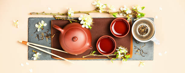 istock Asian Tea set on stone slate board, ceramic teapot, cups, dried tea and spring branches 1352665242