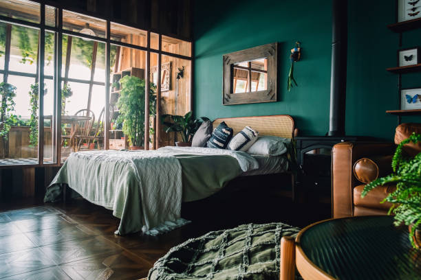 un elegante interior de dormitorio tipo loft con muebles de ratán de color marrón y elementos de madera con pared de color verde oscuro. decorado con plantas - queen size bed fotografías e imágenes de stock