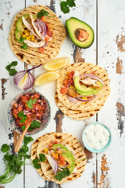 istock Mexican tacos with grilled chicken, avocado, corn kernels, tomato, onion, cilantro and salsa old white wooden table. Traditional Mexican and Latin american street food. Top view. 1352666538