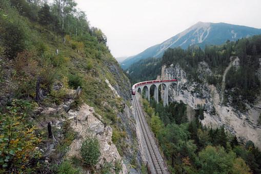 view from above on Landwasserviadukt in Switzerland with red train passing