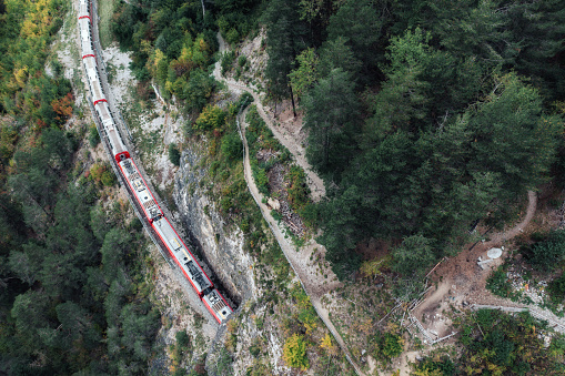 aerial view on on red train entering tunnel of the Landwasserviadukt railroad bridge in Switzerland