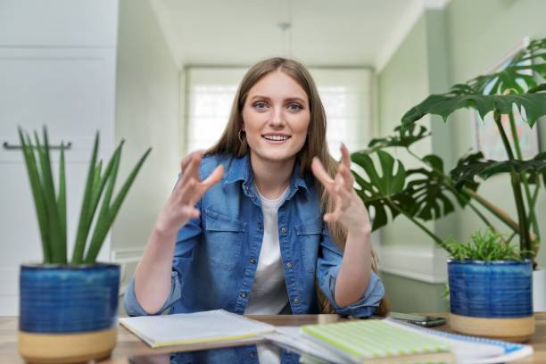 istock Positive smiling female university student talking looking at webcam, at home. 1352671533