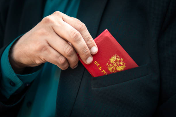 tarjeta de identidad roja de fsb. hombre con tarjeta de identificación. hombre con un traje azul muestra una tarjeta de identificación roja o un pase. la mano de un hombre con un traje azul saca una tarjeta de identificación roja del bolsillo de su chaq - caste system fotografías e imágenes de stock