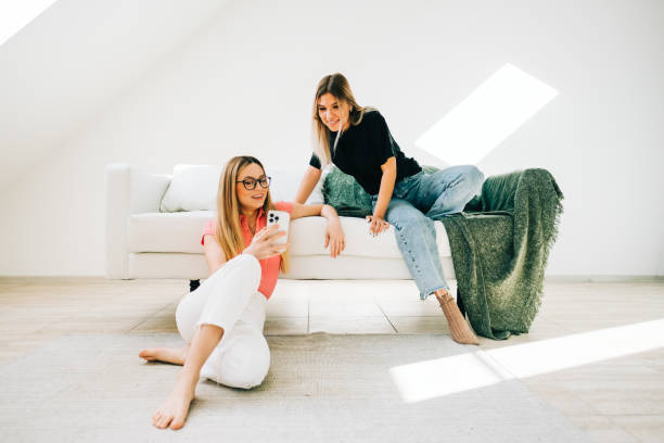 istock Friends together browsing internet, sitting on sofa and looking on smartphone screen. 1352671798