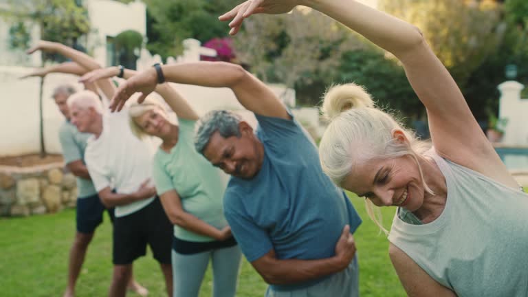 4k video footage of a group of mature people practicing yoga in a garden