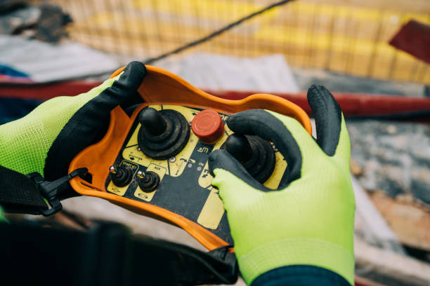 Engineer holding and working with remote control for operating crane. Unrecognizable construction worker/operator is holding industrial remote wireless console to control overhead crane with joystick at construction site. hand elevator stock pictures, royalty-free photos & images