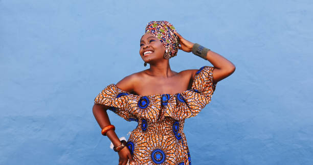 Shot of a beautiful young woman wearing traditional African clothing against a blue background stock photo