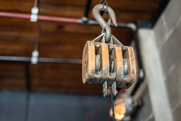 An ancient wood chain hoisting and hook equipment block which is hanging from ceiling for indoor decoration in industrial style cafe. Close-up and selective focus.