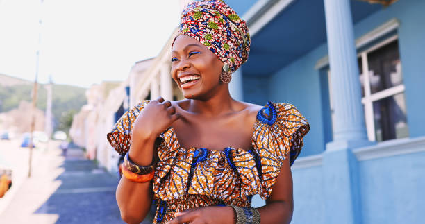 都市の背景に対して伝統的なアフリカの服を着て美しい若い女性のショット - 伝統 ストックフォトと画像