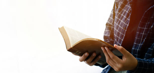 leer la biblia primer plano de la mano de una mujer leyendo la biblia junto a la ventana fondo blanco - preacher fotografías e imágenes de stock