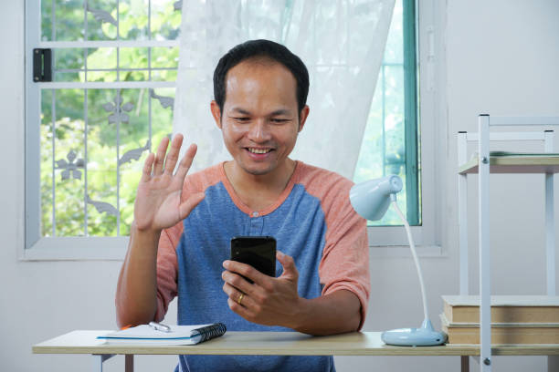 istock asian man using a smart phone for video call to freind. 1352678574