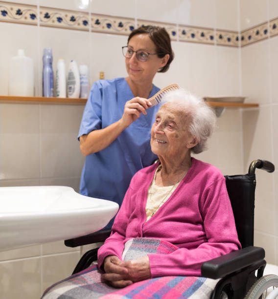 Home Caregiver with senior woman in bathroom stock photo