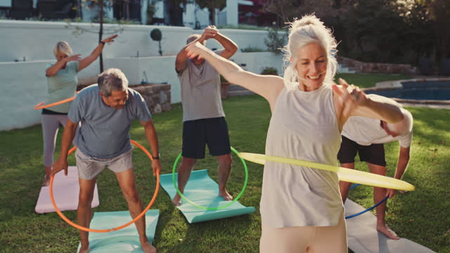 4k video footage of a group of mature friends playing with hoola hoops together