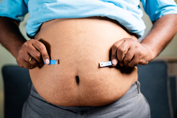 homem obeso não saudável irreconhecível verificando gordura do estômago ou da cintura usando fita métrica antes da dieta em casa - conceito de sofrer excesso de peso corporal devido a hábitos de junk food - overweight dieting men unhealthy eating - fotografias e filmes do acervo