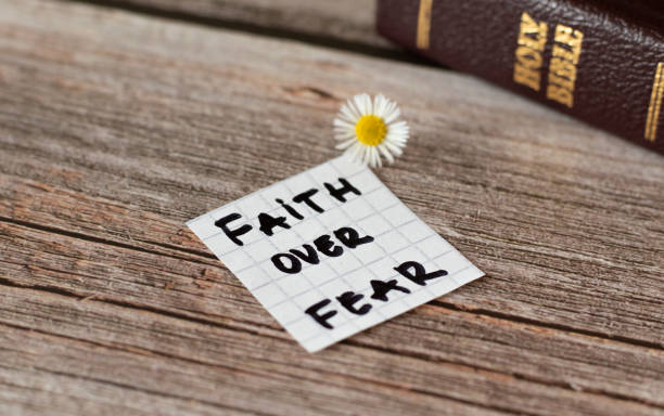 Faith over fear-inspiring handwritten quote with Holy Bible Book. on wooden table. stock photo