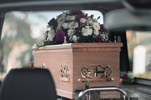 Flores sobre un ataúd en exhibición dentro de un coche fúnebre en un funeral photo