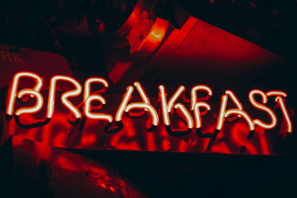 istock Neon sign phrase 'Breakfast'. Bright glowing red neon sign in cafe interior 1352688480