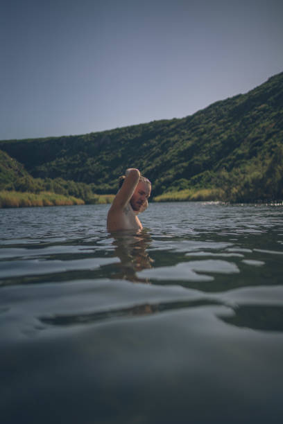 istock Young man goes for a swim at forested lakeshore 1352688881