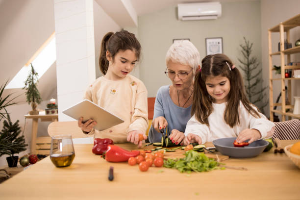 istock Two cute sisters making lunch with grandma 1352694061