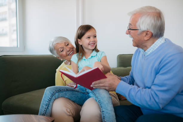istock Grandparents reading a book with granddauther 1352698353