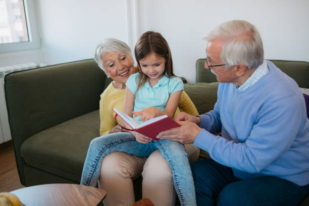 istock Grandparents reading a book to granddauther 1352698357