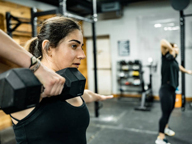 istock Young woman lifting weights in the Gym 1352698400