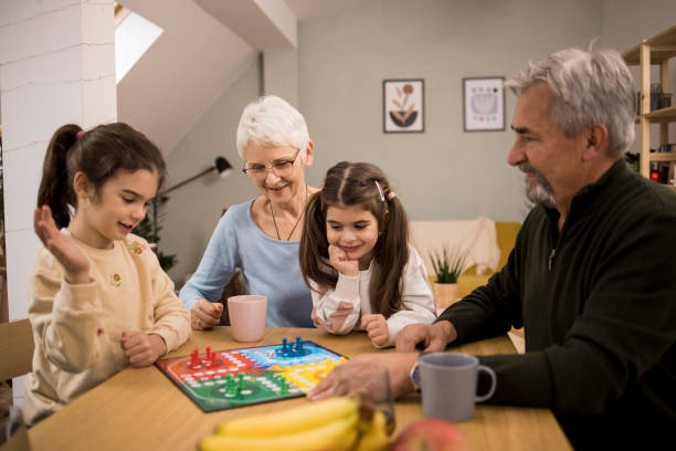 istock Two cute sisters playing a board game with grandparents 1352700444